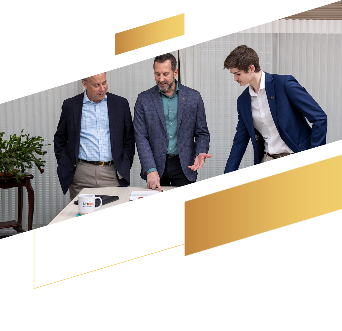 Three men in business attire stand around a table, discussing investment documents and management strategies in a modern office setting.